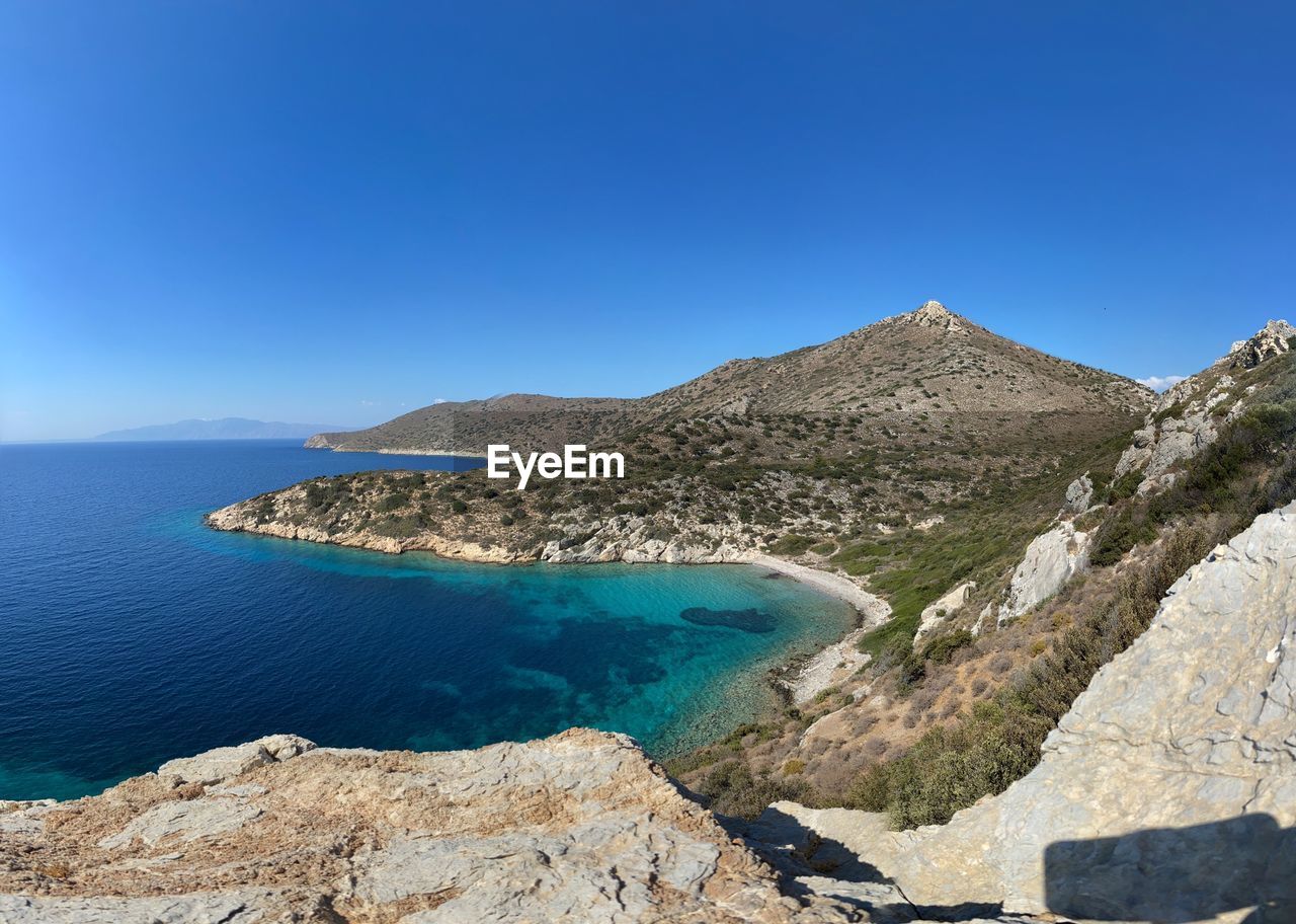 Panoramic view of sea and mountains against clear blue sky