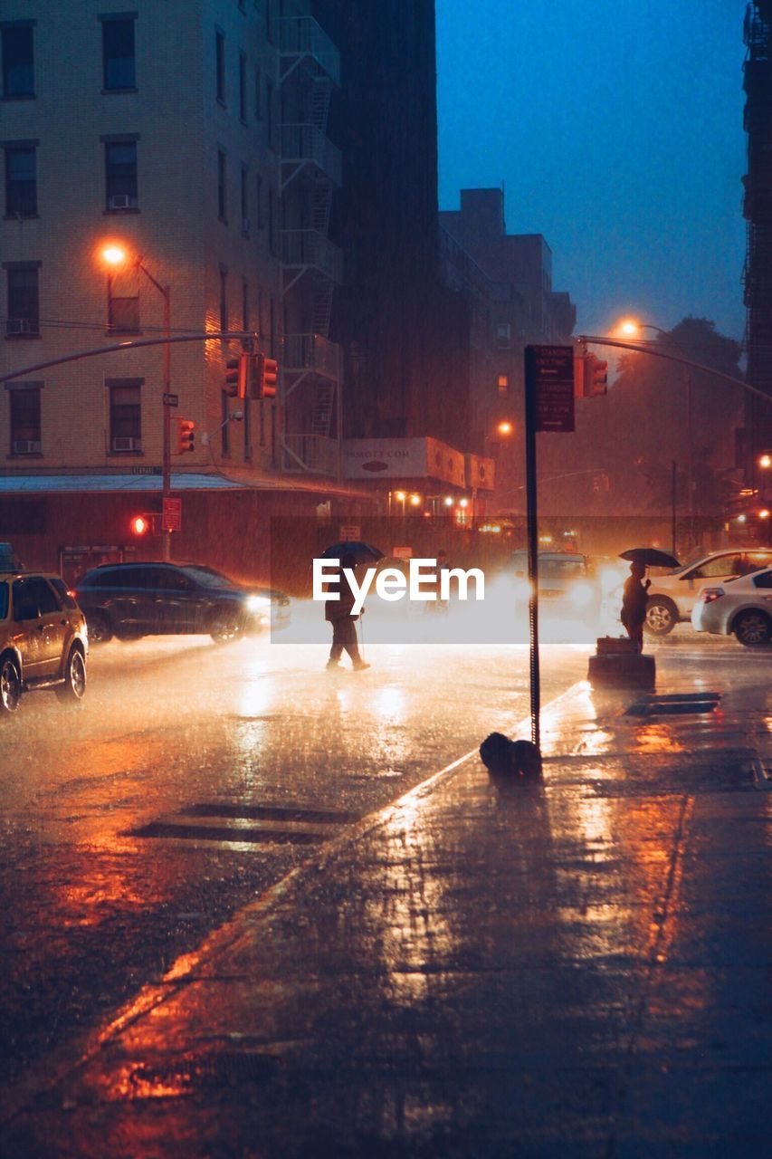 Vehicles on road along buildings at night