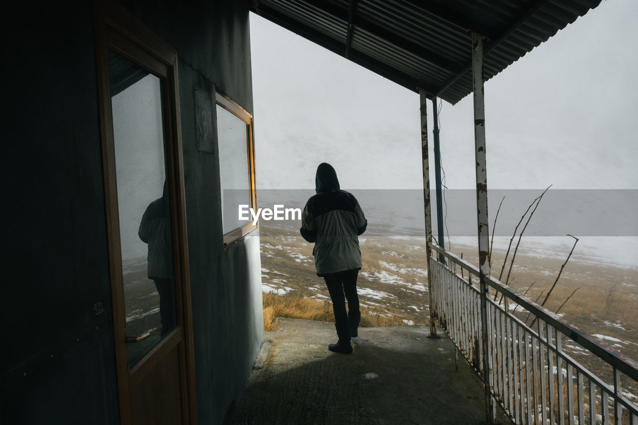 Rear view of man walking in front of house
