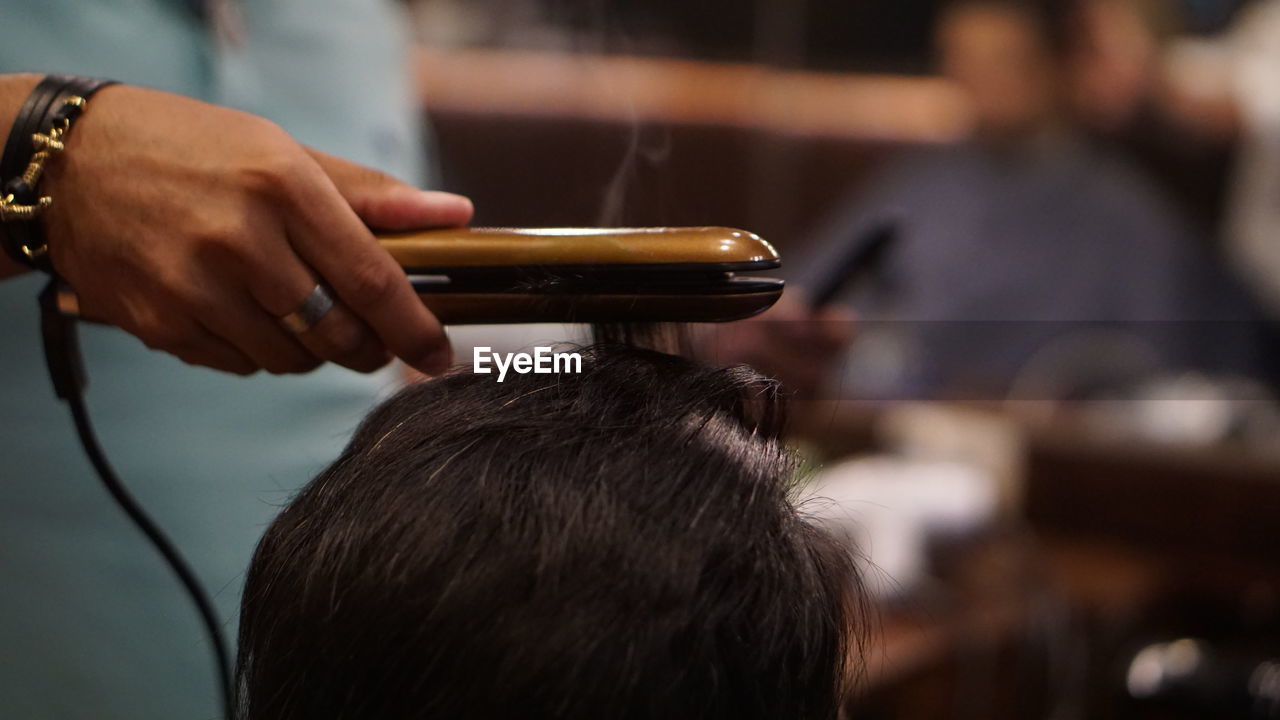 Close-up of hairdresser straightening hair 