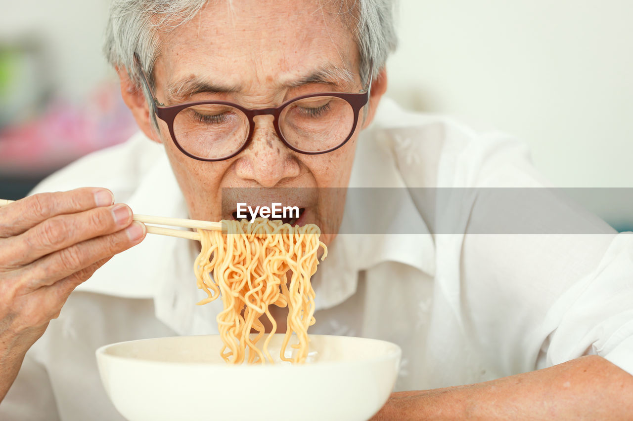 Senior woman eating noodles