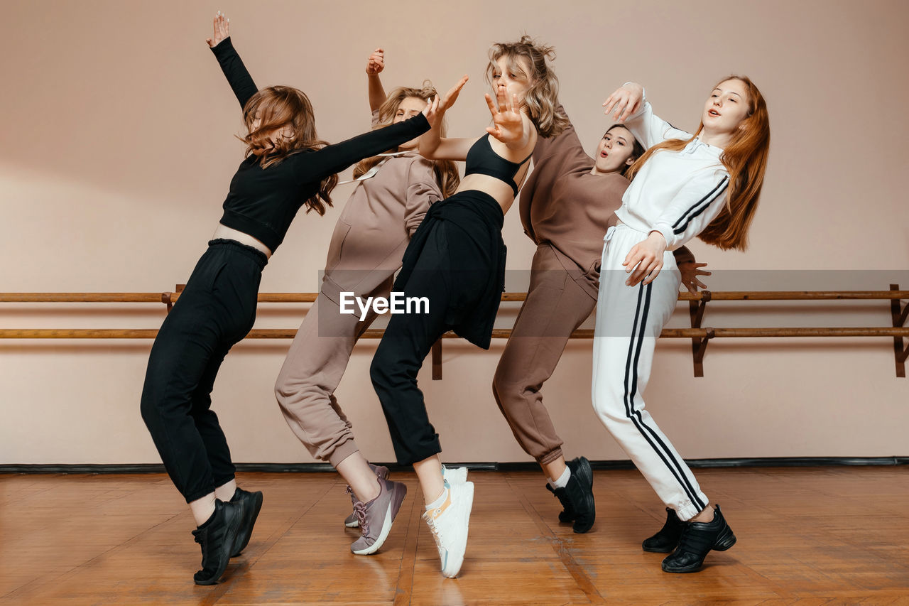 Group of girls in sportswear, performing elements of house dance in a dance studio, dancing with