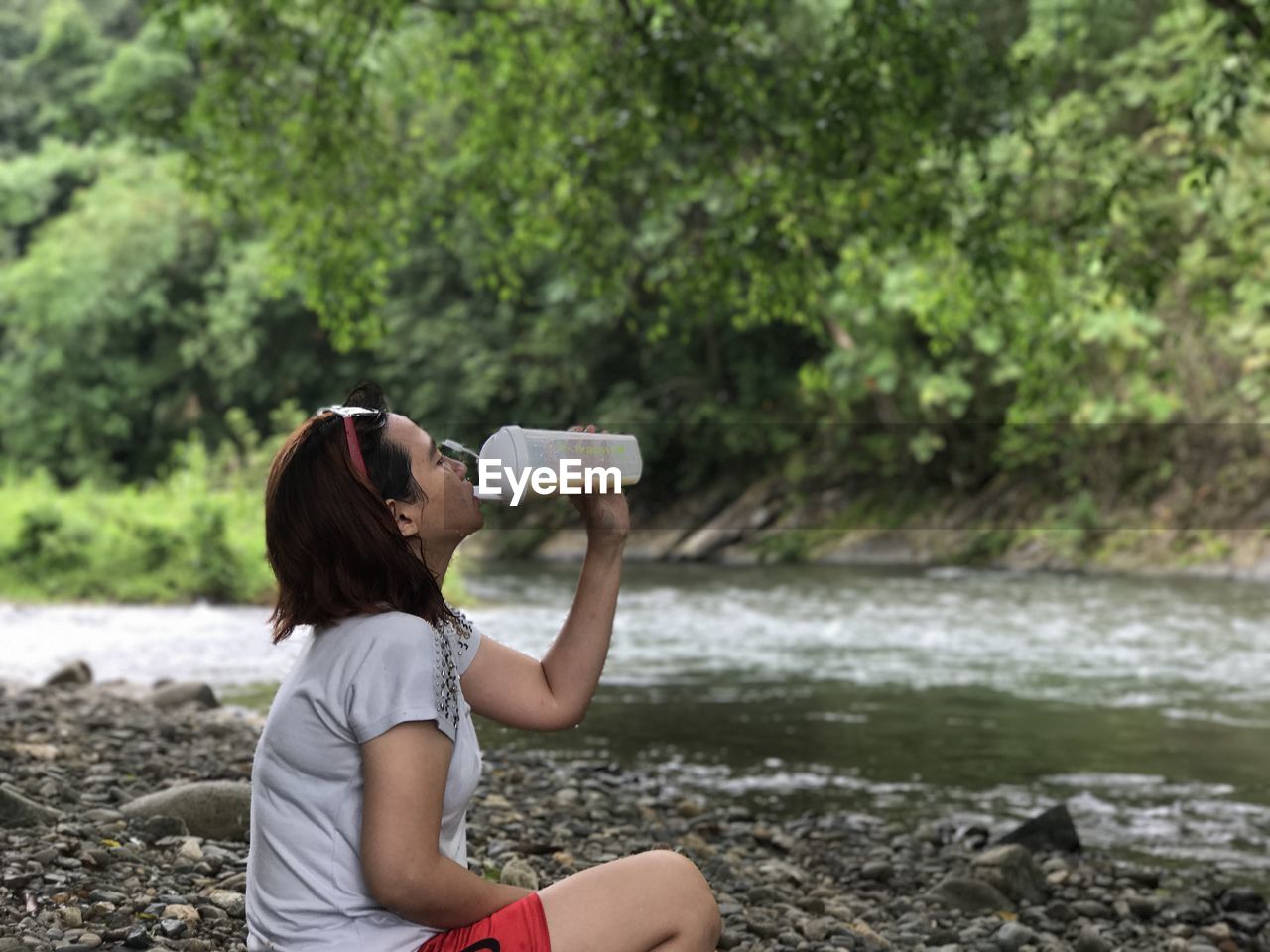 Side view of young woman drinking by river