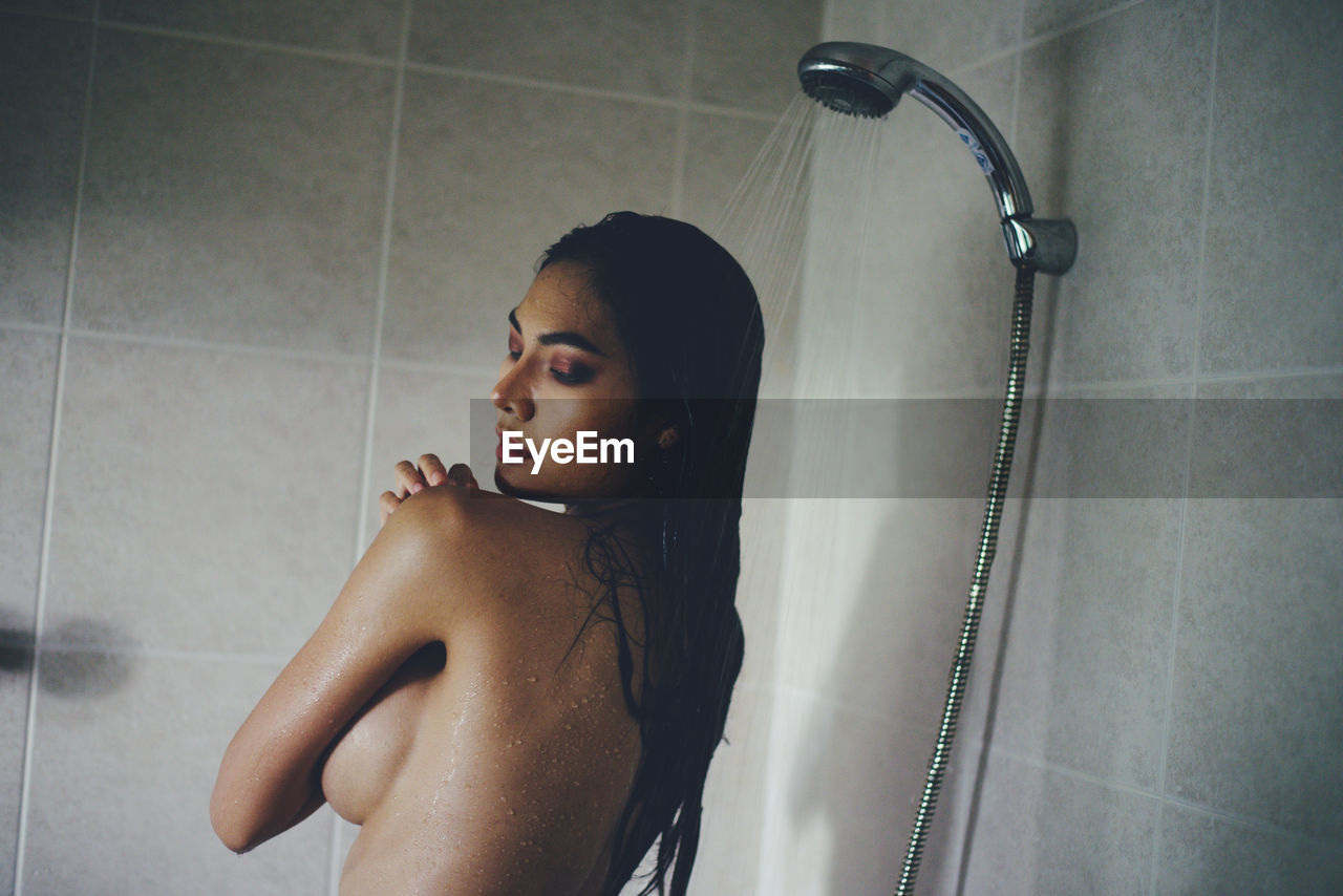 Seductive woman taking shower in bathtub