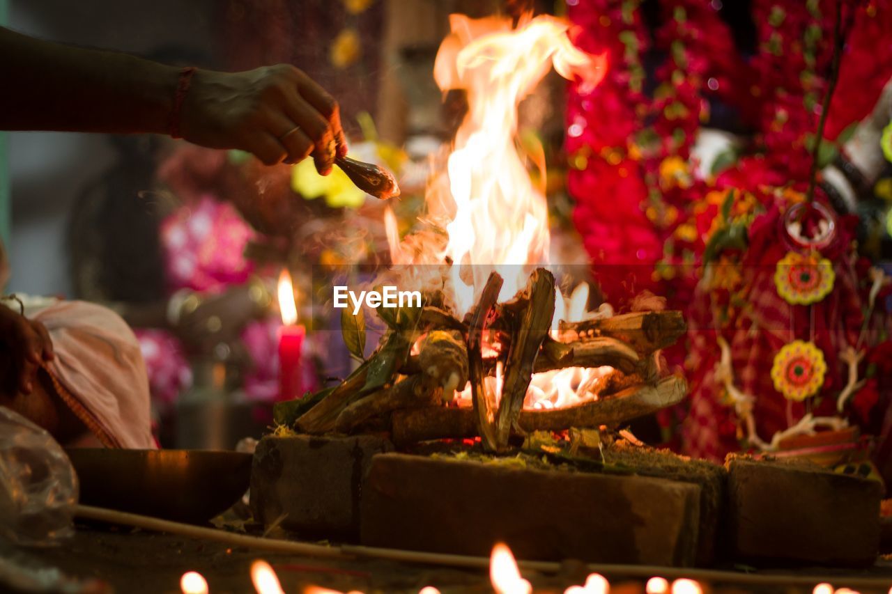 Cropped hand of man pouring ghee in fire at ceremony