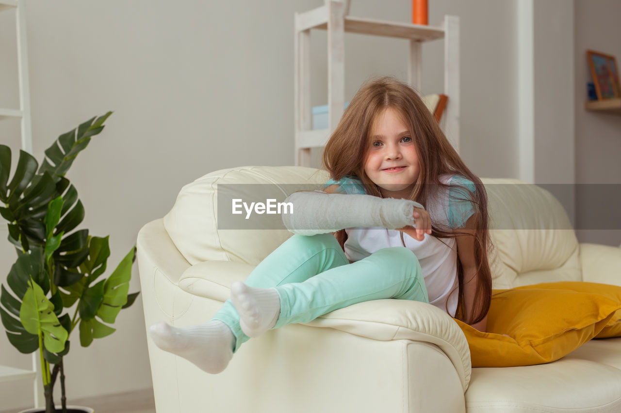 Portrait of smiling woman sitting on sofa at home