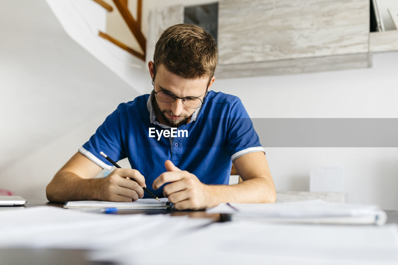 Dedicated young male student doing mathematics homework at table