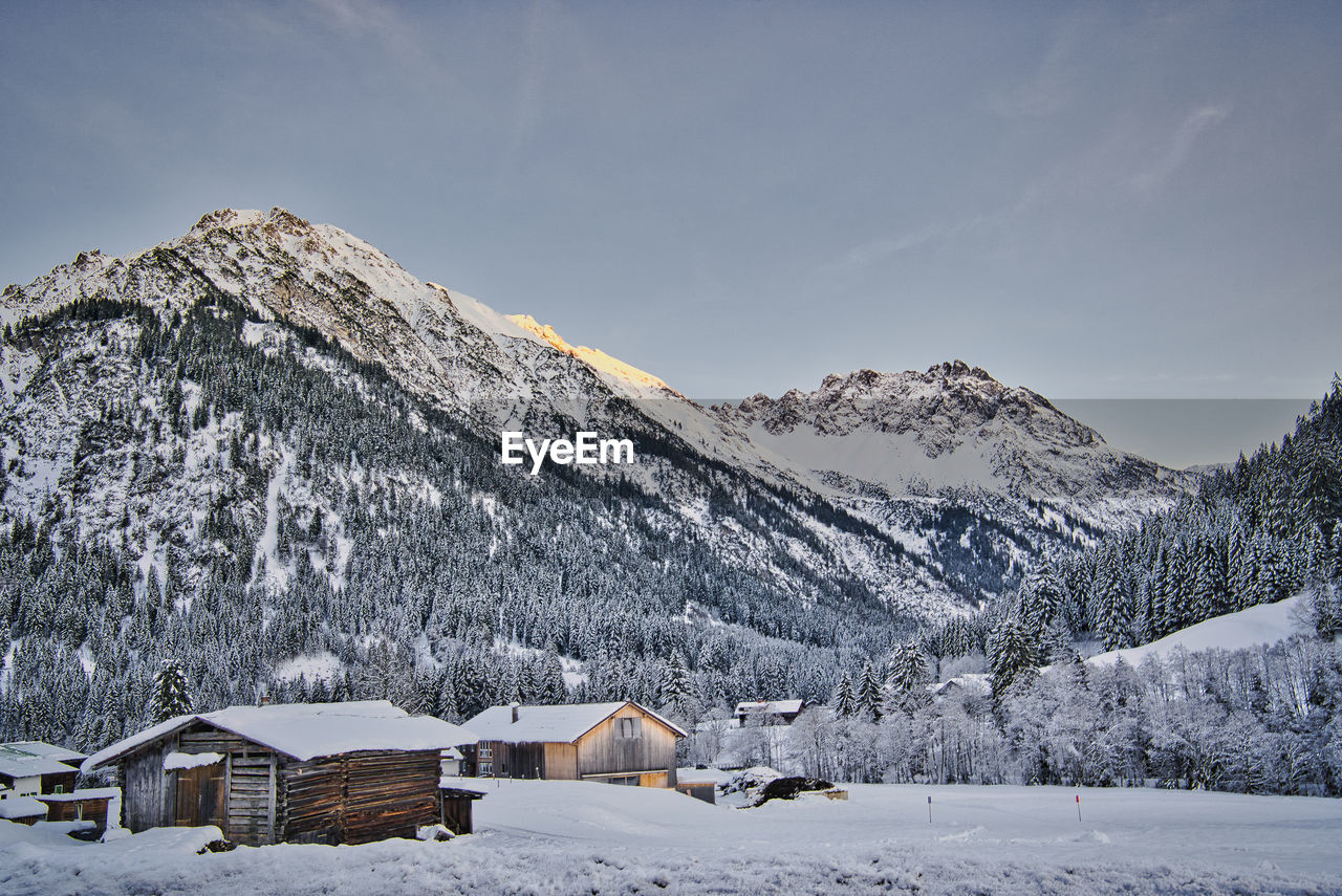 Snow covered landscape and houses against sky