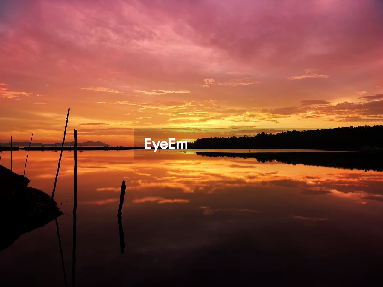 Scenic view of lake against dramatic sky during sunset