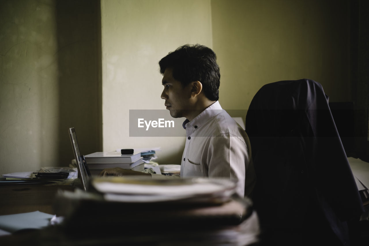 Side view of businessman working at desk in office