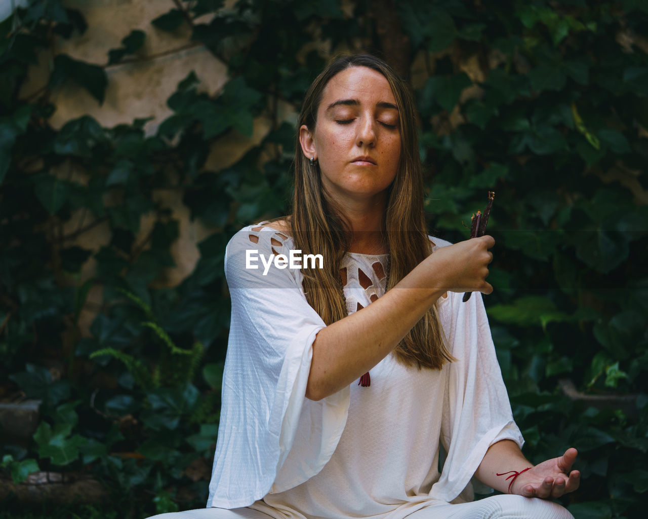 Close-up of young woman meditating while sitting outdoors