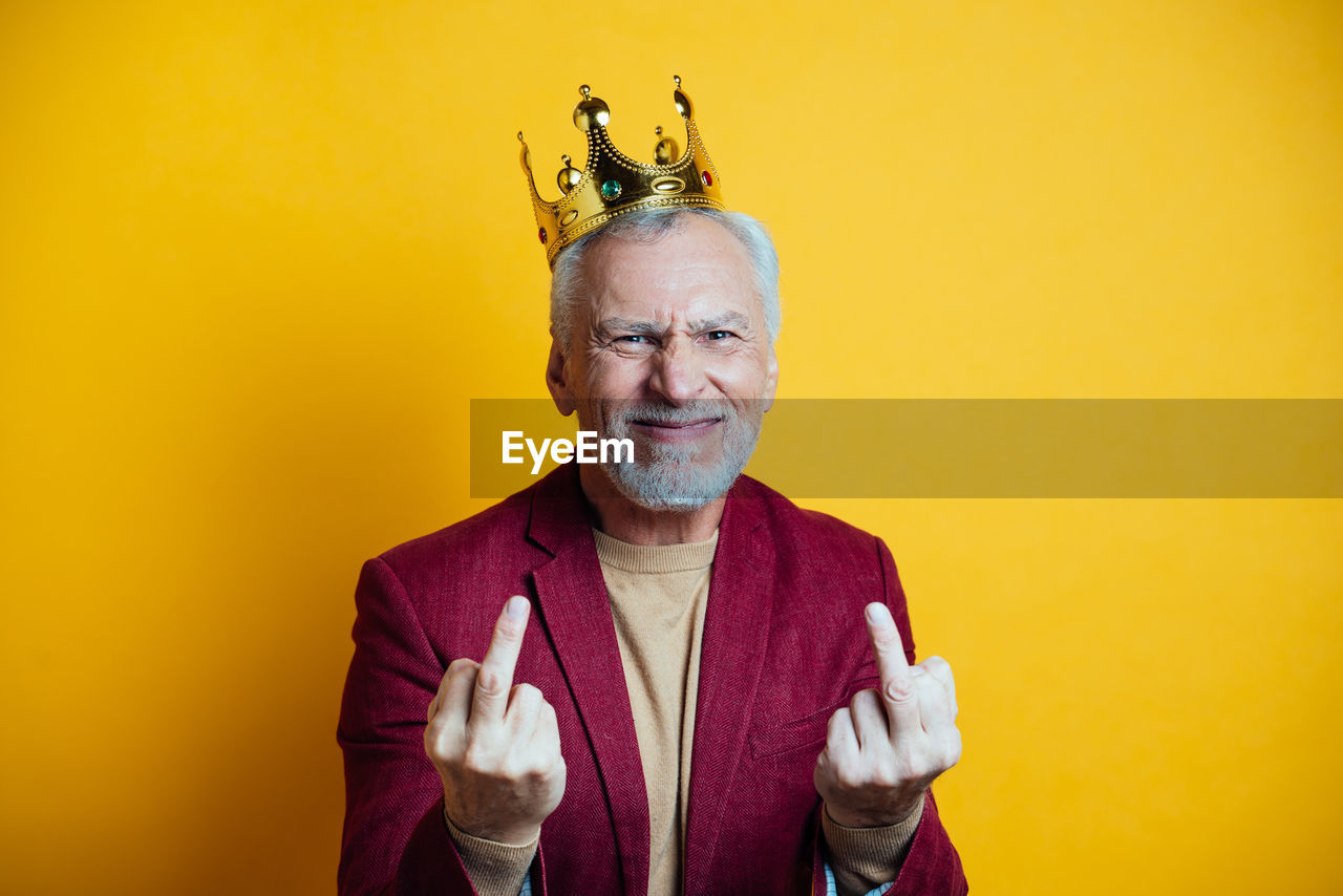 Portrait of smiling man gesturing against yellow background