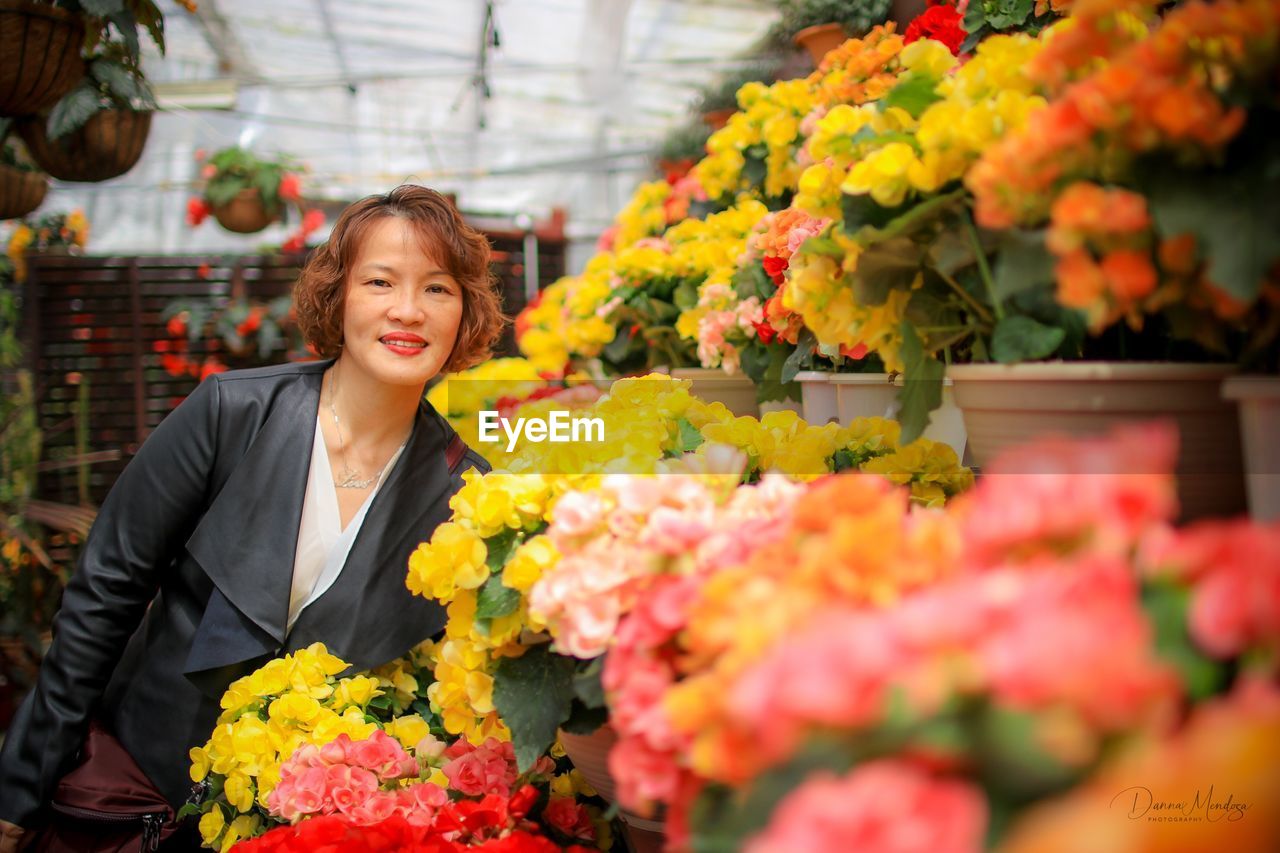 Portrait of smiling mature woman standing by colorful flowers in shop