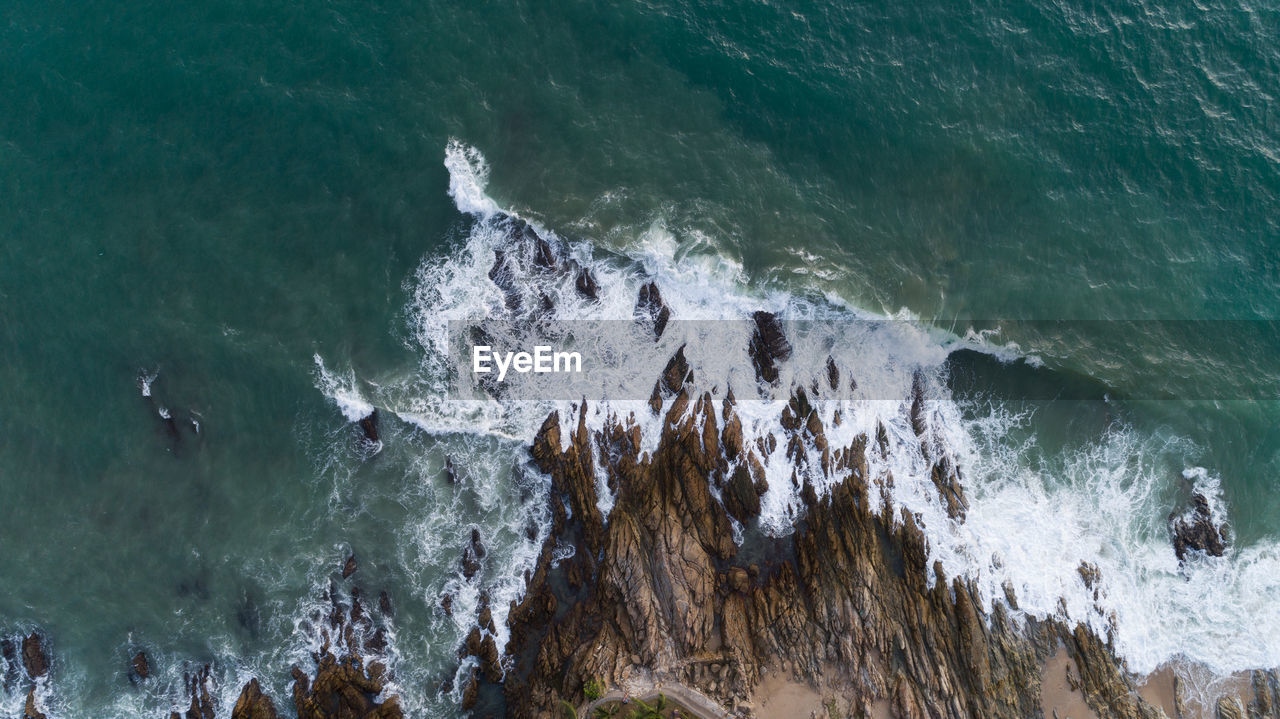 Aerial view of waves splashing on rock 