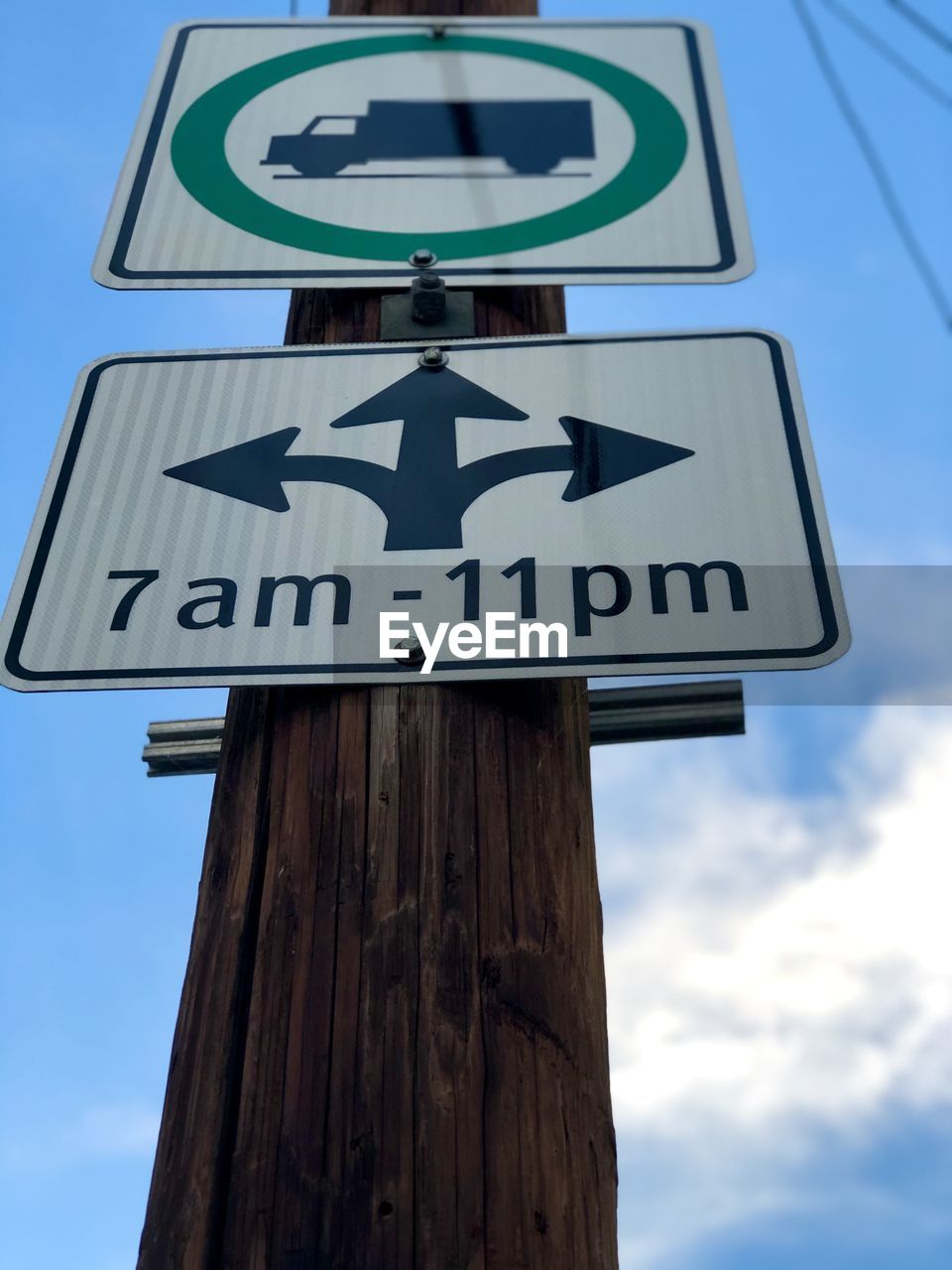 LOW ANGLE VIEW OF ROAD SIGN ON WOODEN POSTS