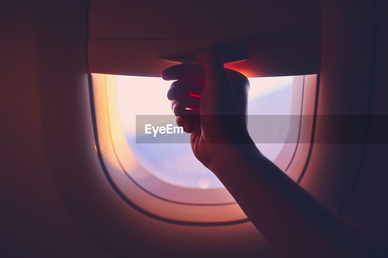 Cropped hand of person by airplane window