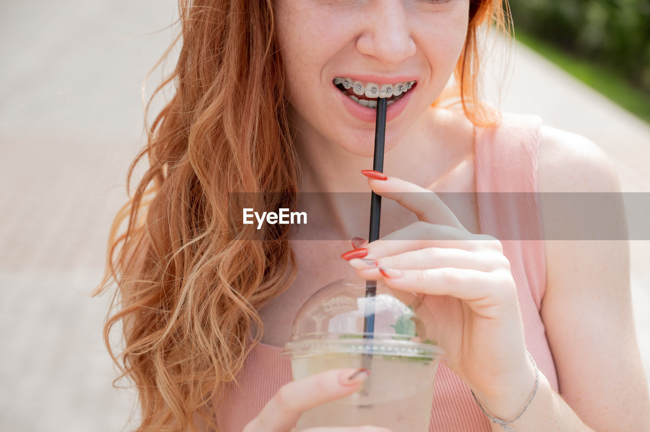 Midsection of woman drinking lemonade outdoors