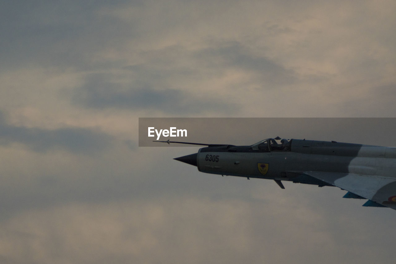 LOW ANGLE VIEW OF AIRPLANE FLYING IN SKY DURING SUNSET