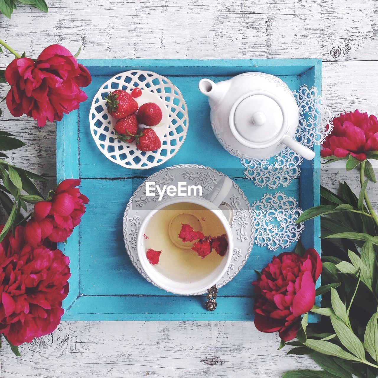 High angle view of flowers with tea cup and strawberries on table