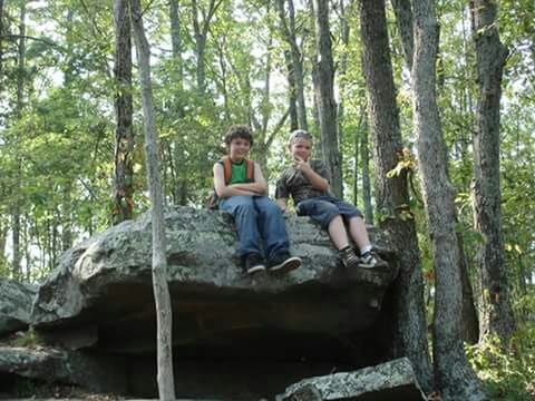 PORTRAIT OF YOUNG WOMAN SITTING ON TREE STUMP