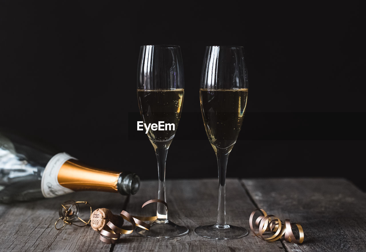 Two glasses of champagne and empty bottle with black background.