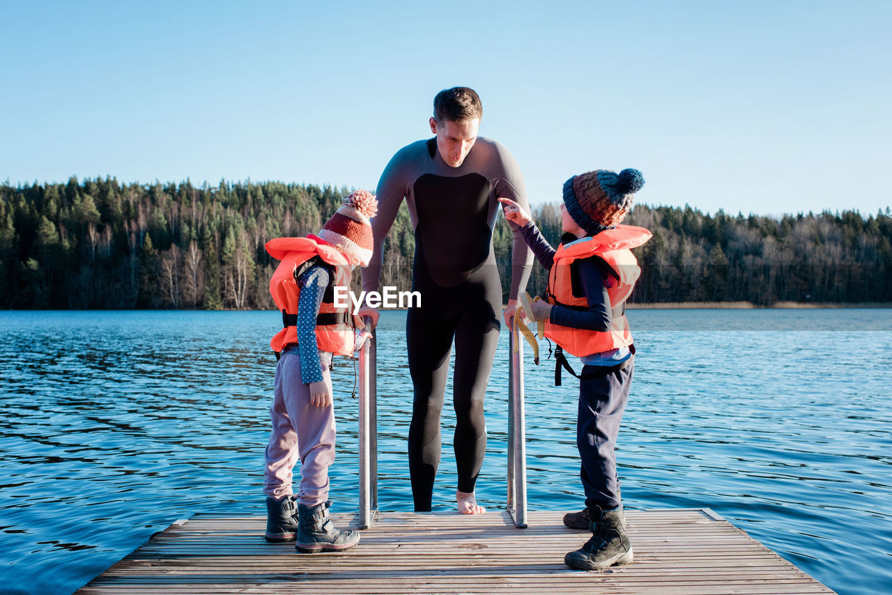 Father going cold water swimming whilst at the beach with his kids