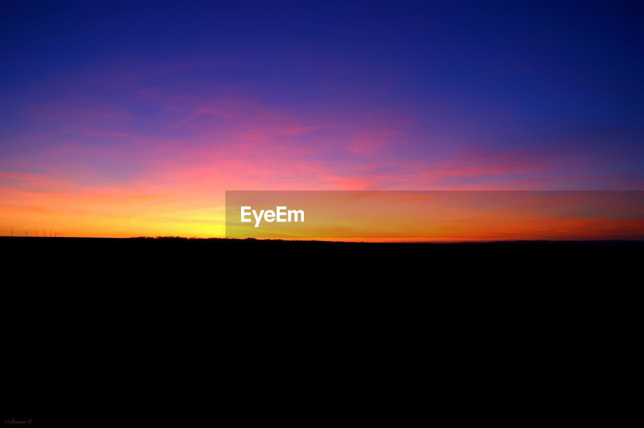 Scenic view of silhouette field against moody sky