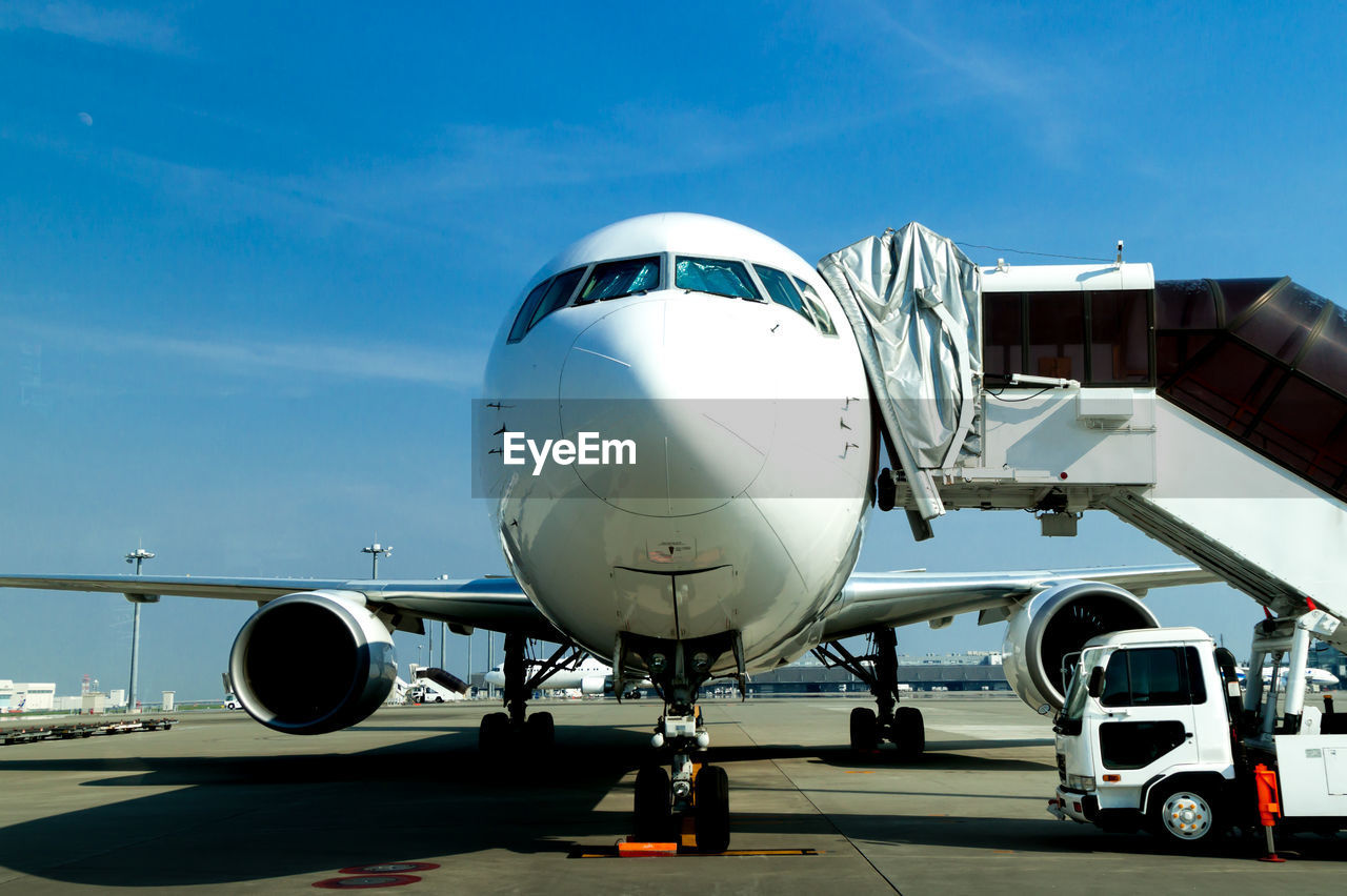 Front view of airplane on airport runway against sky