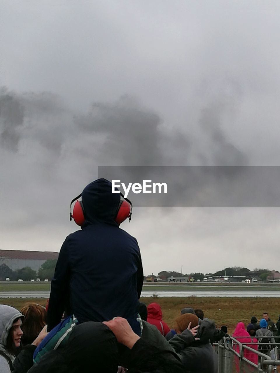 Rear view of father carrying son on shoulders against smoke