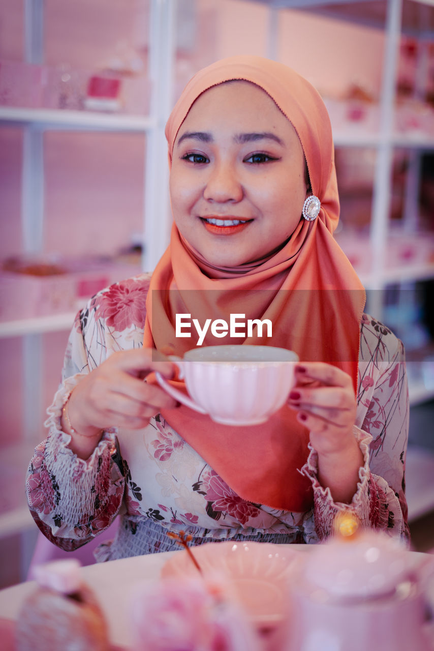 PORTRAIT OF A YOUNG WOMAN DRINKING COFFEE