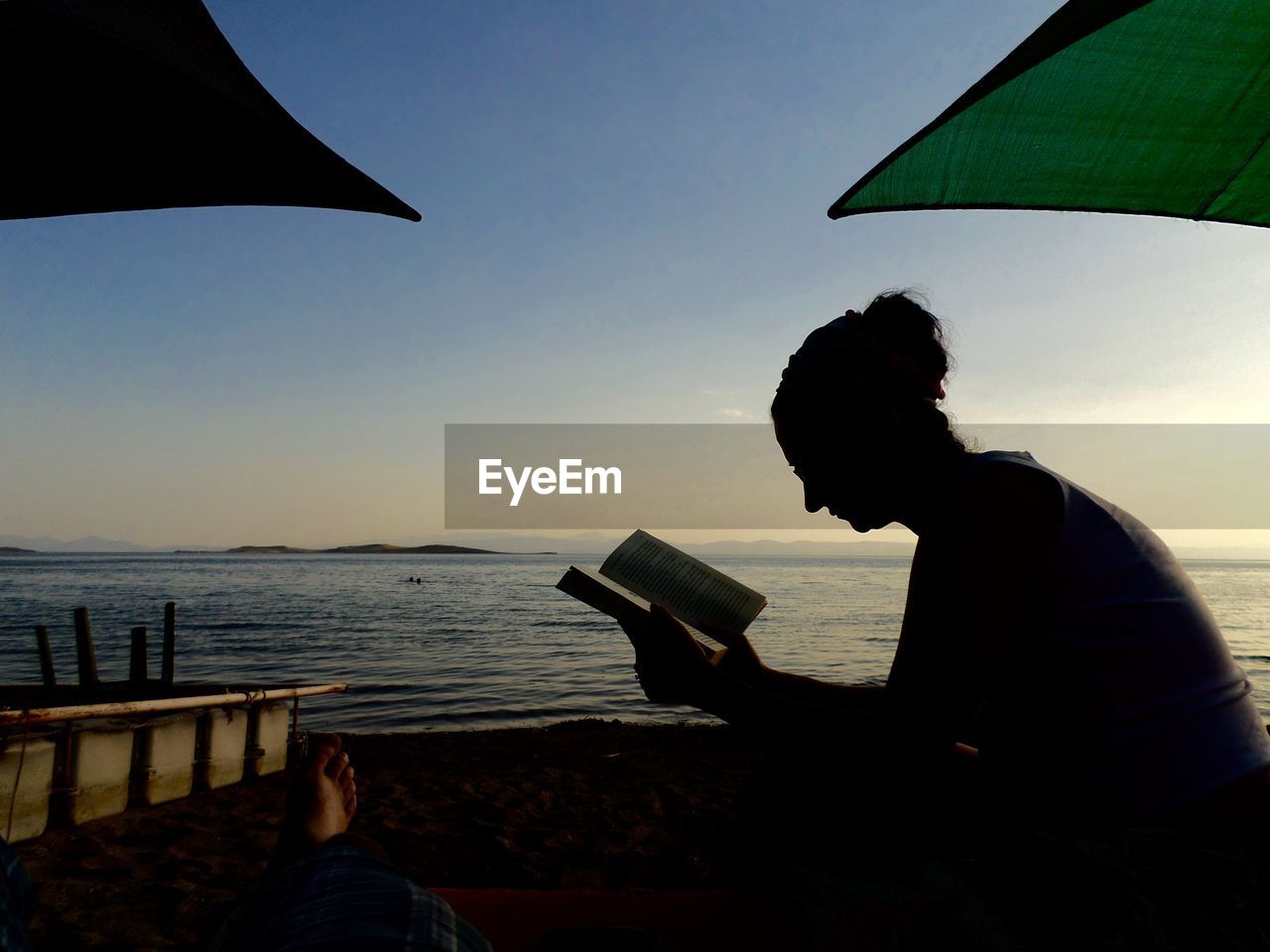 Silhouette woman reading book at beach
