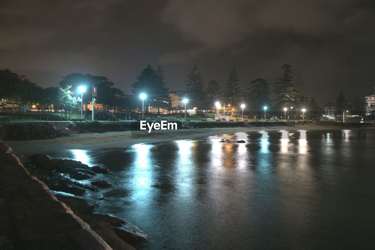 Illuminated beach against sky at night