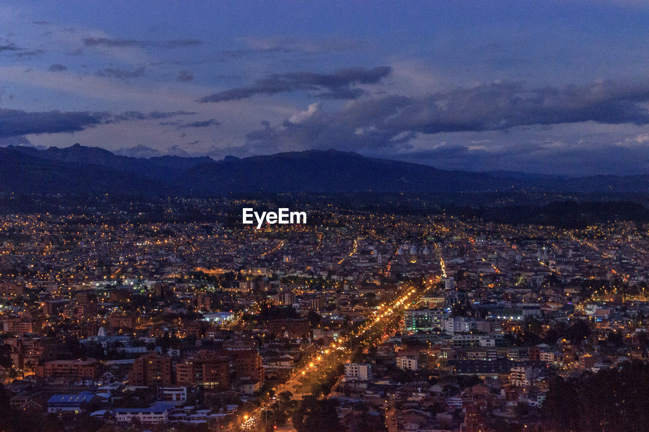 AERIAL VIEW OF ILLUMINATED CITYSCAPE AGAINST SKY AT DUSK