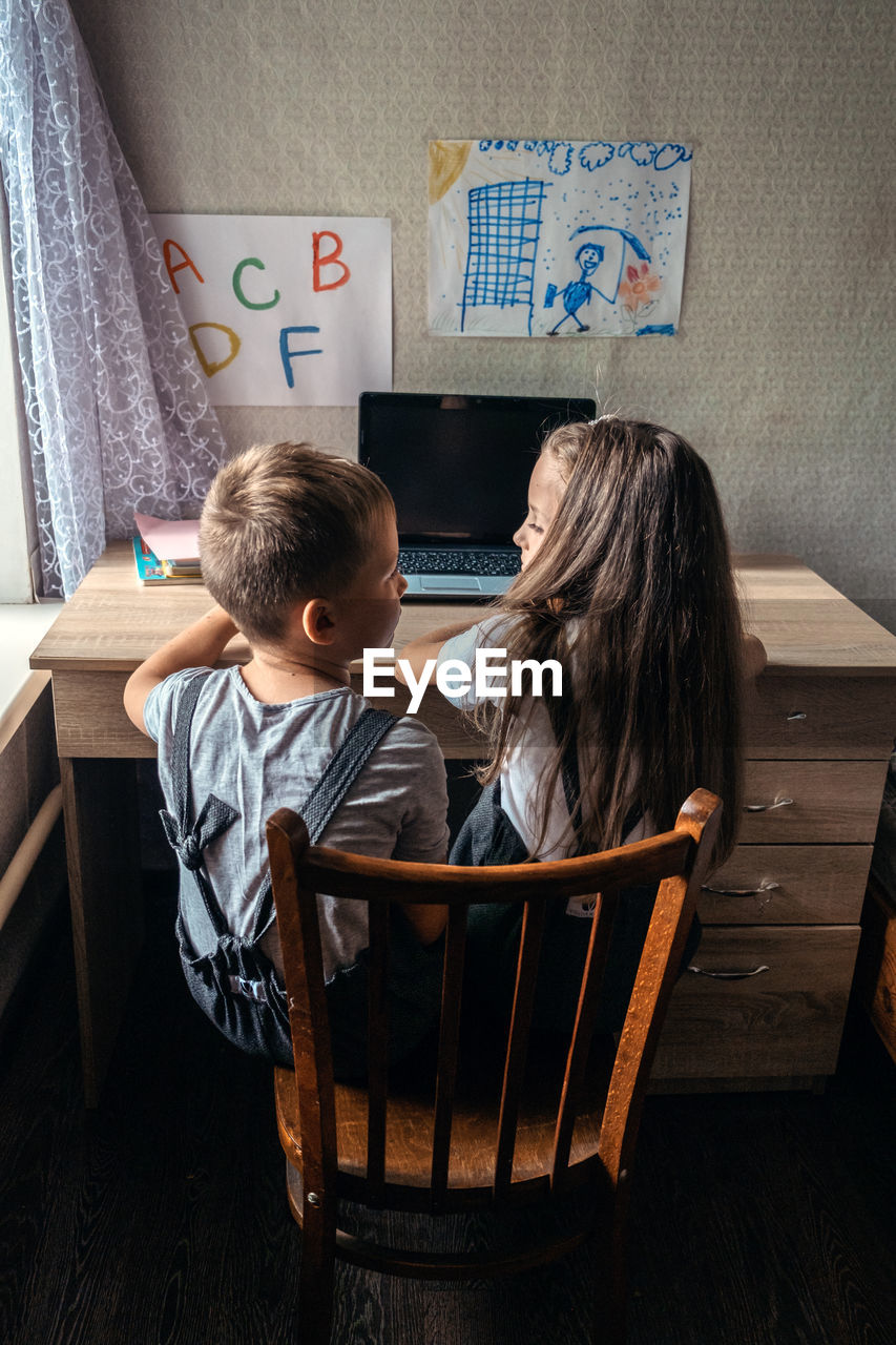 Group of schoolkids or friends wearing headphones sitting near laptop at home. family, school pupil