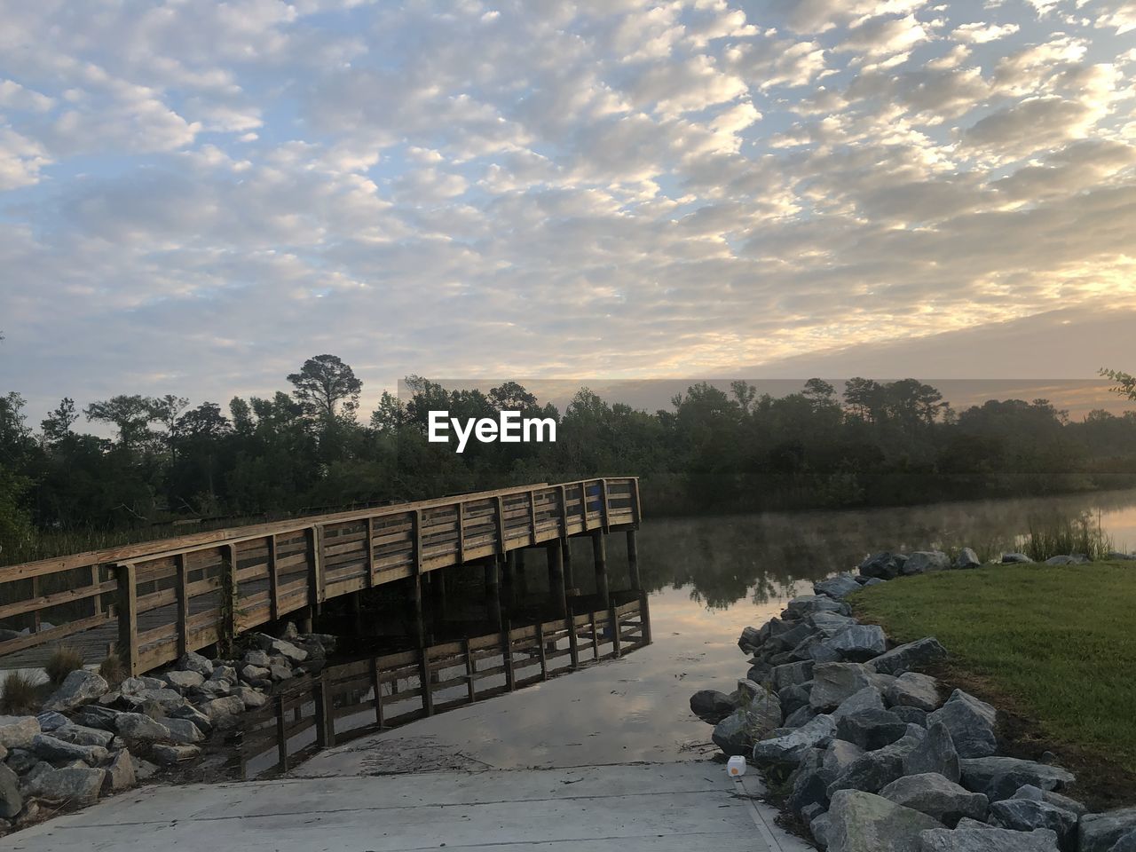 ROCKS BY LAKE AGAINST SKY DURING SUNSET