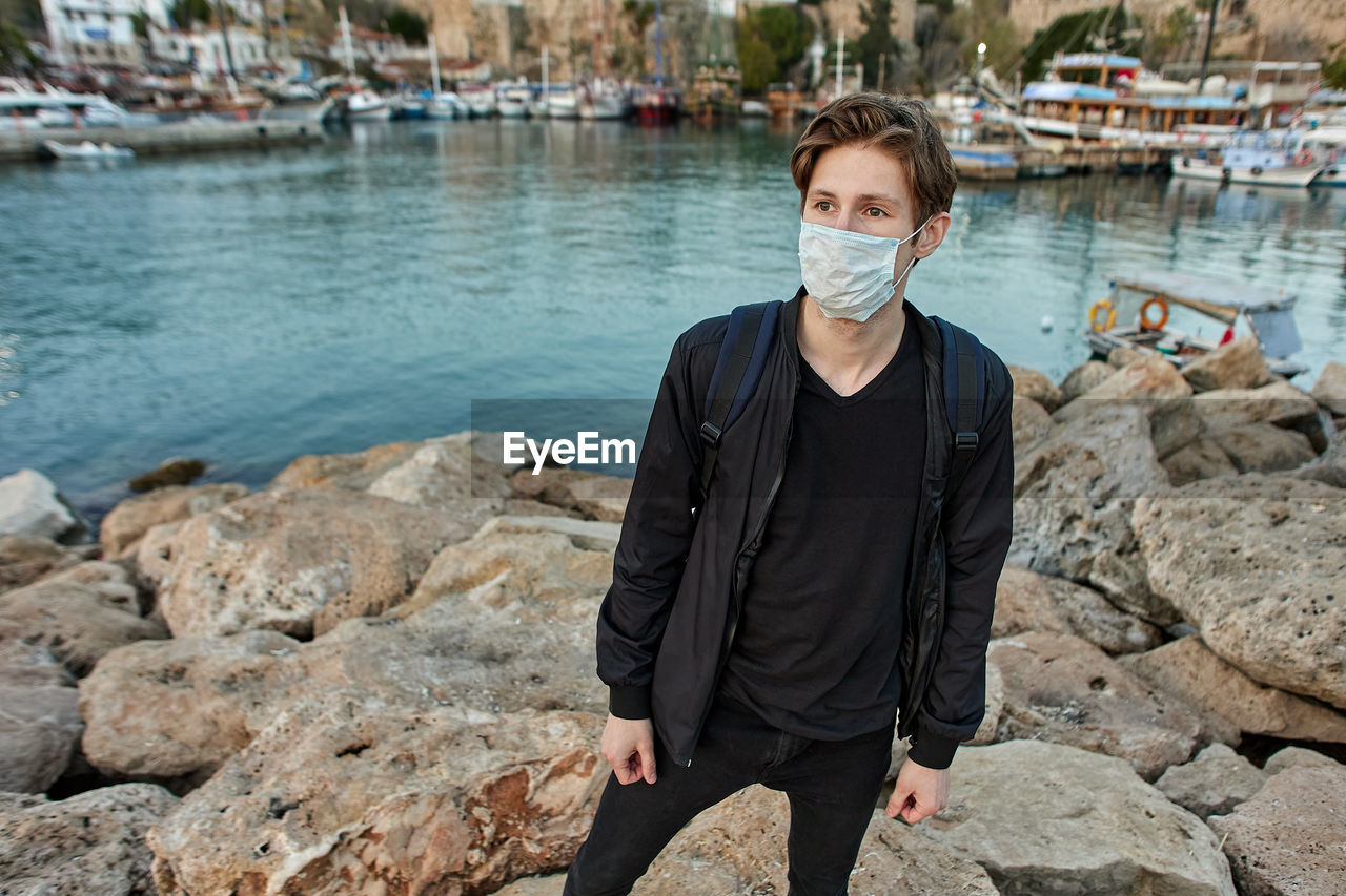 Portrait of man standing on rock wearing protective face mask