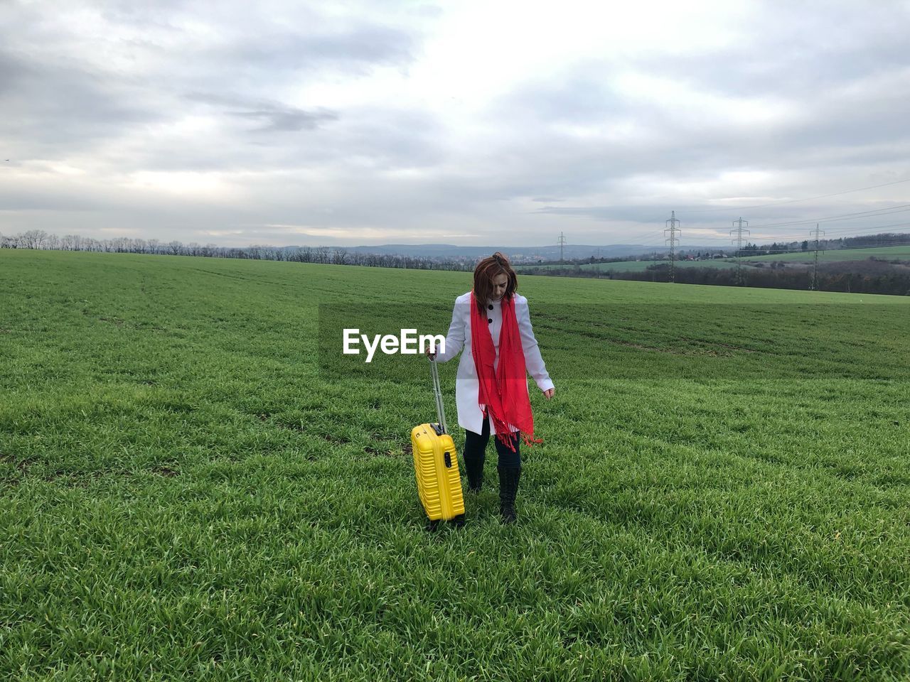 Woman holding luggage while standing on field