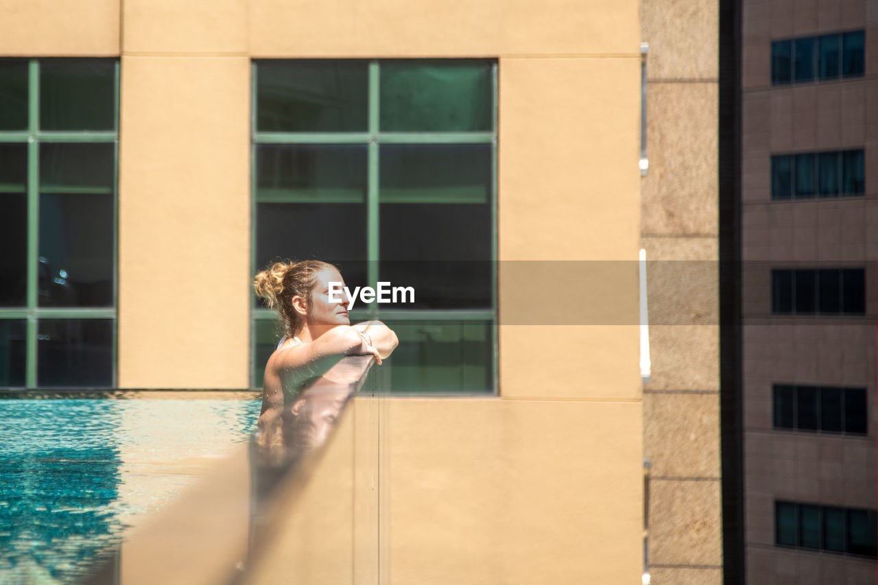 Side view of woman in swimming pool by window