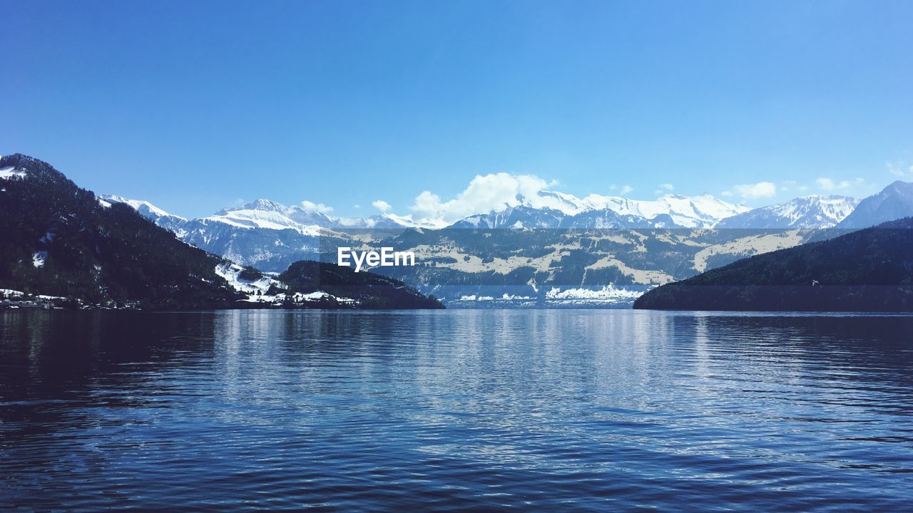 Scenic view of lake and mountains against blue sky