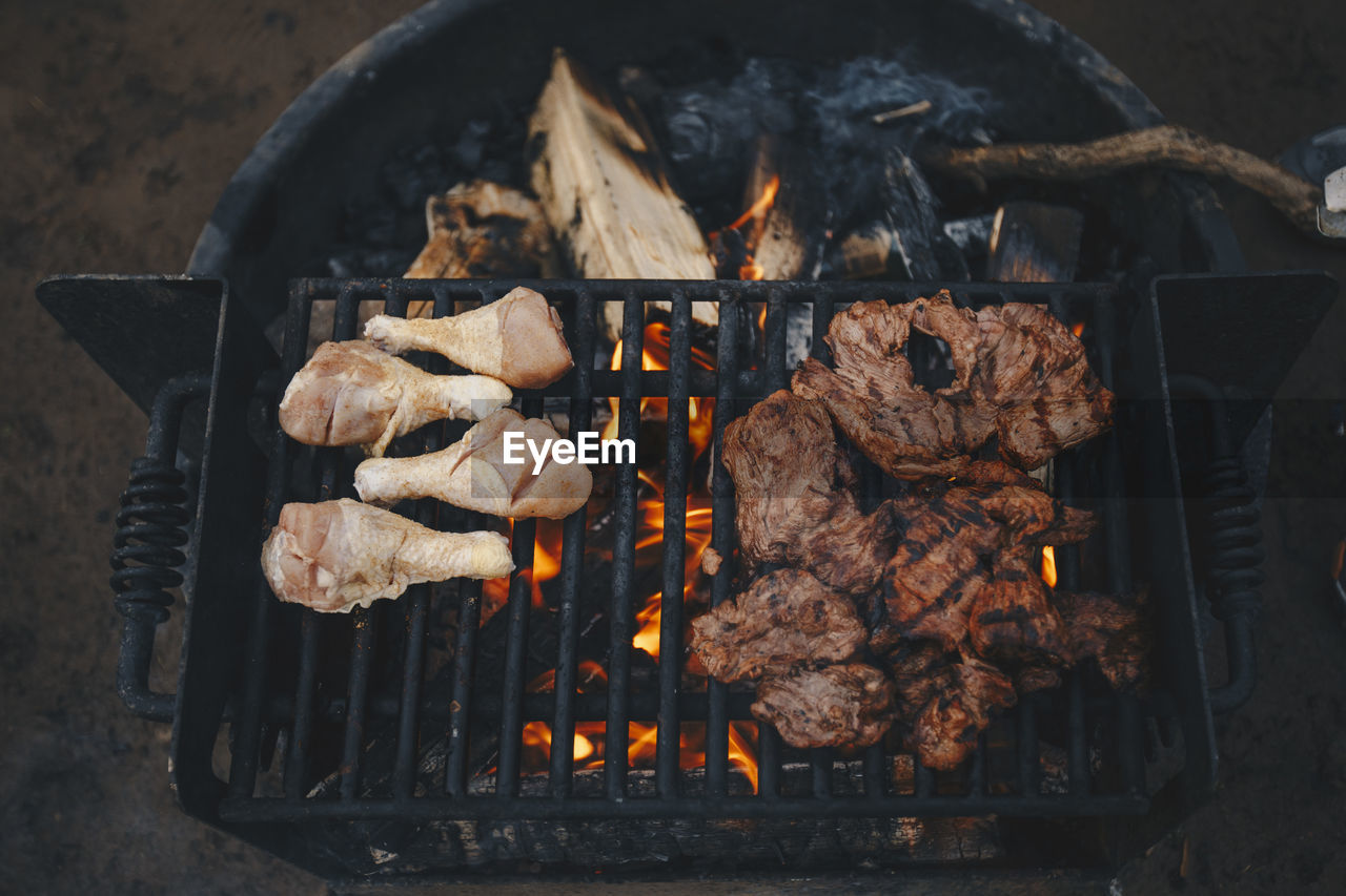 Chicken and meat on a grill at a campsite