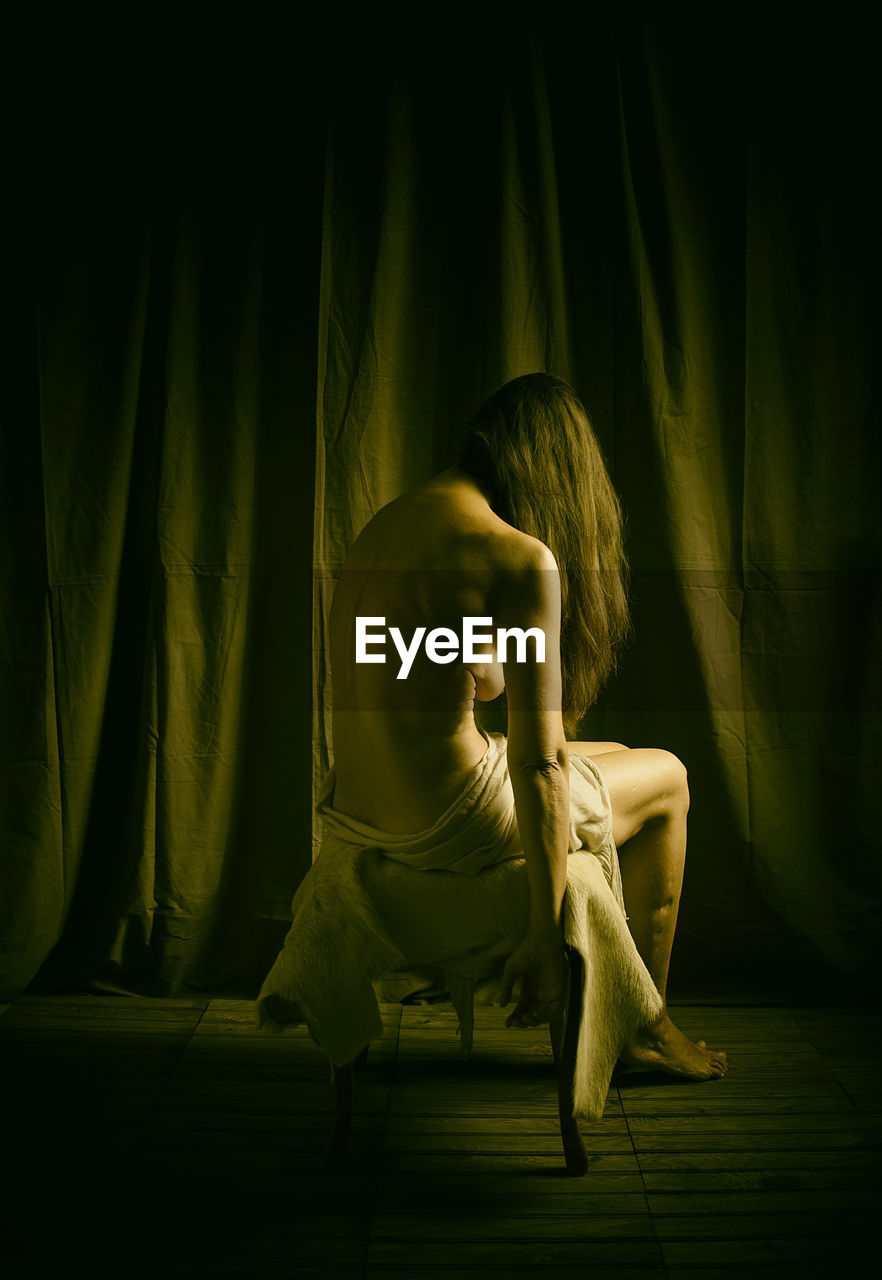 Woman from behind sitting on a stool covered with goatskin ii