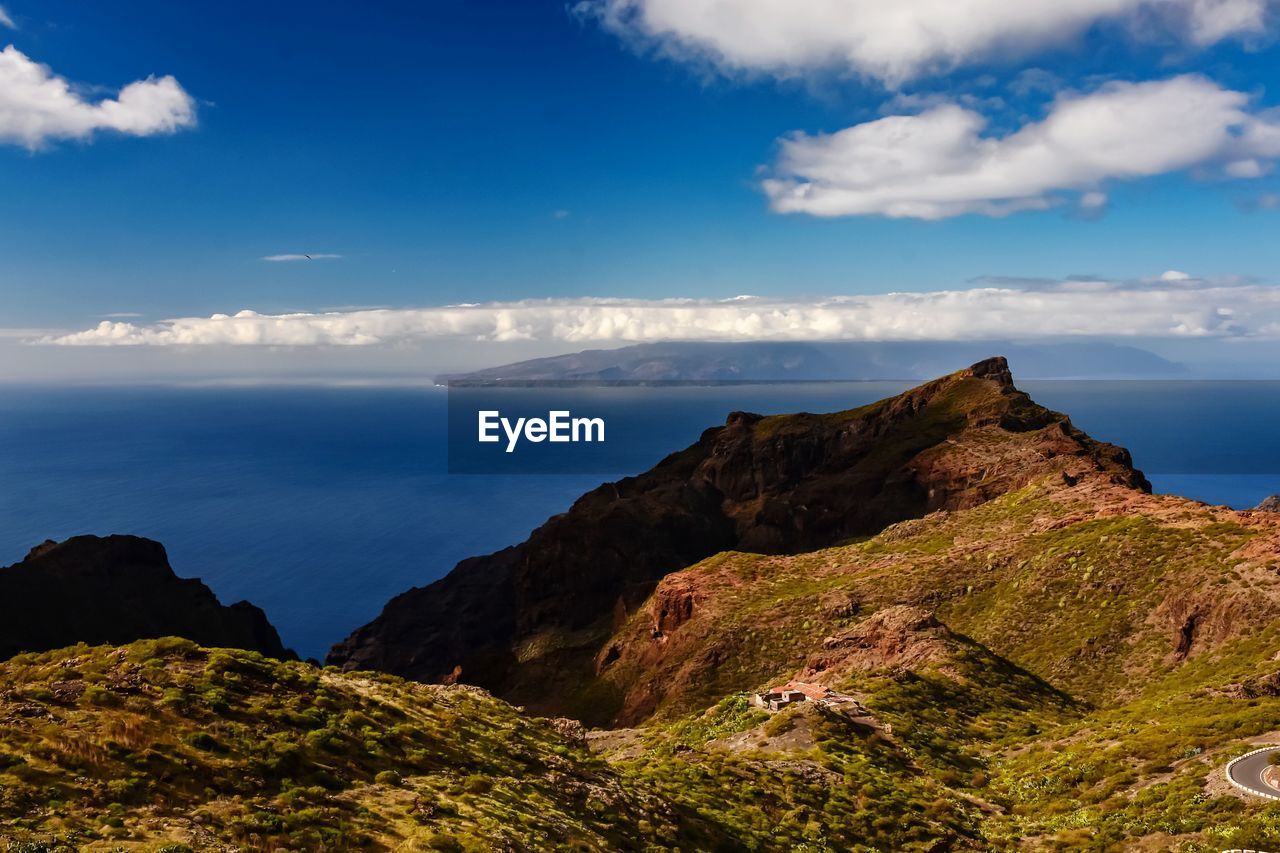 Scenic view of rocky mountains by sea against sky