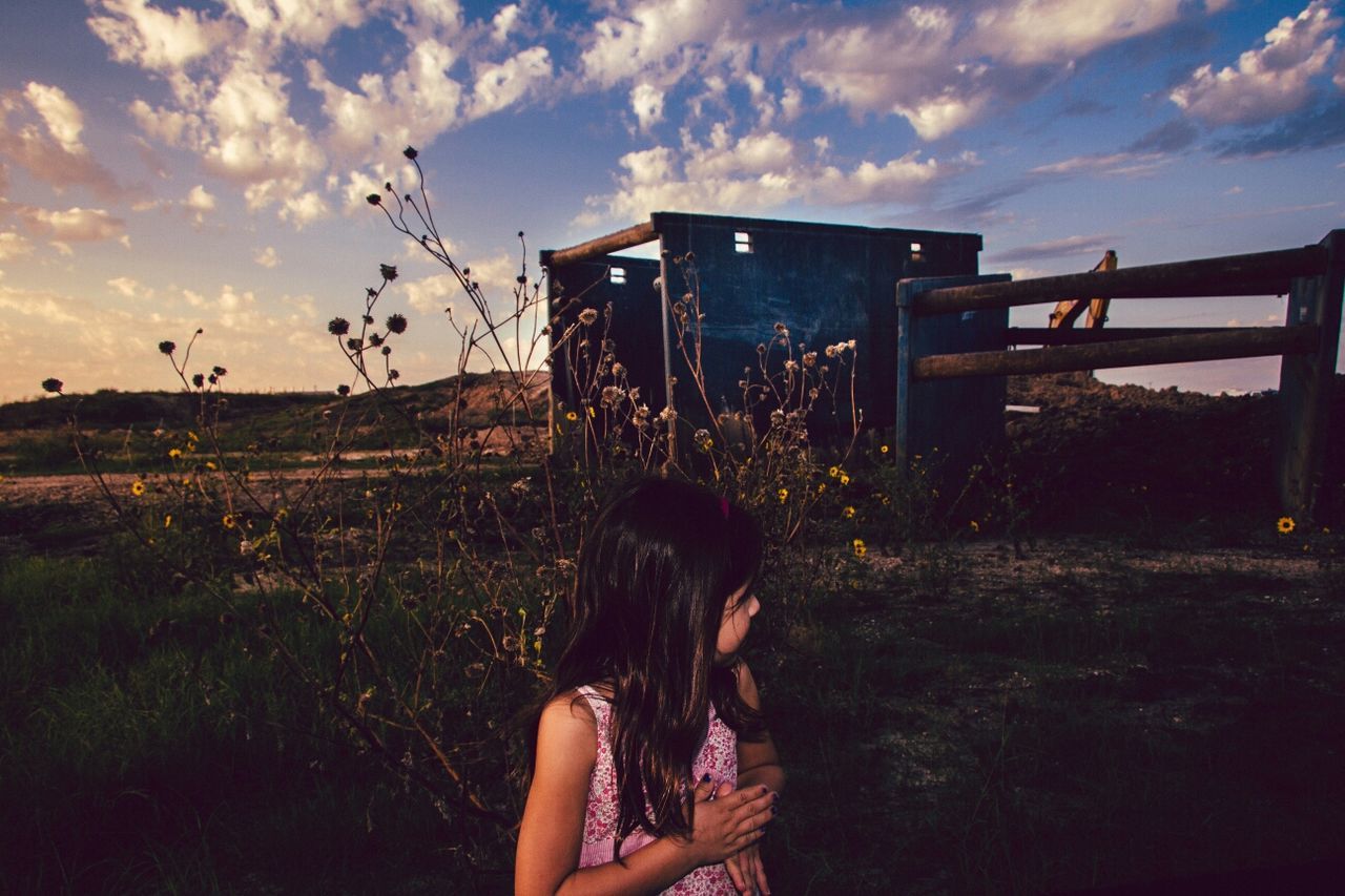 Girl on grassy field against cloudy sky