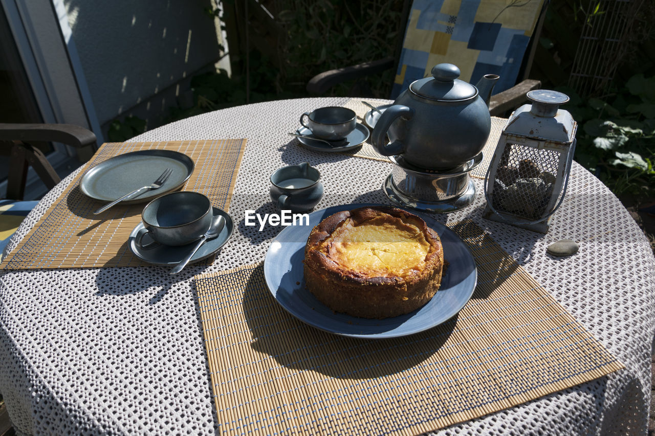 The table on the terrace is set. the blue tea set, plates, cups and the delicious cake.i summer day.