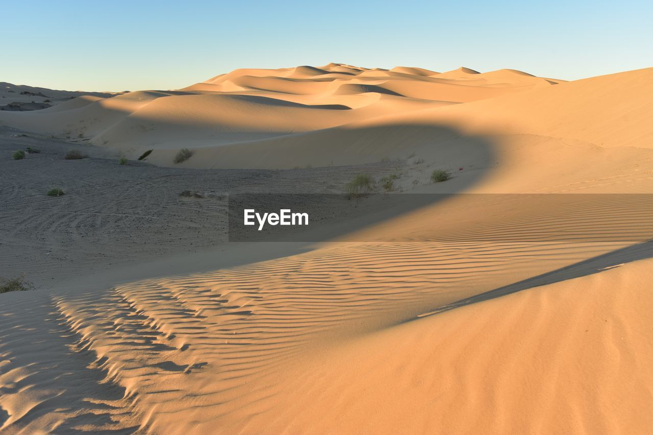 Sand dunes in desert against clear sky