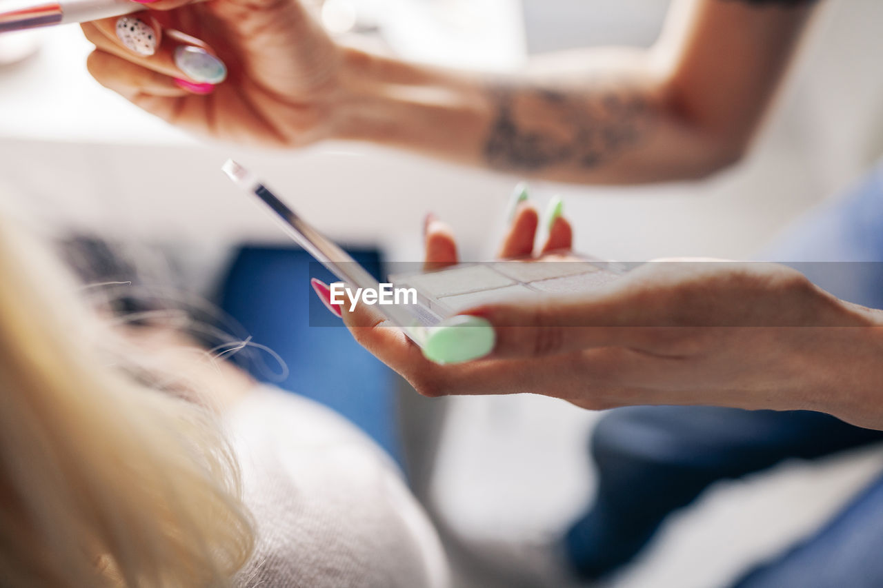 Female make-up artist applying highlighter to model in studio