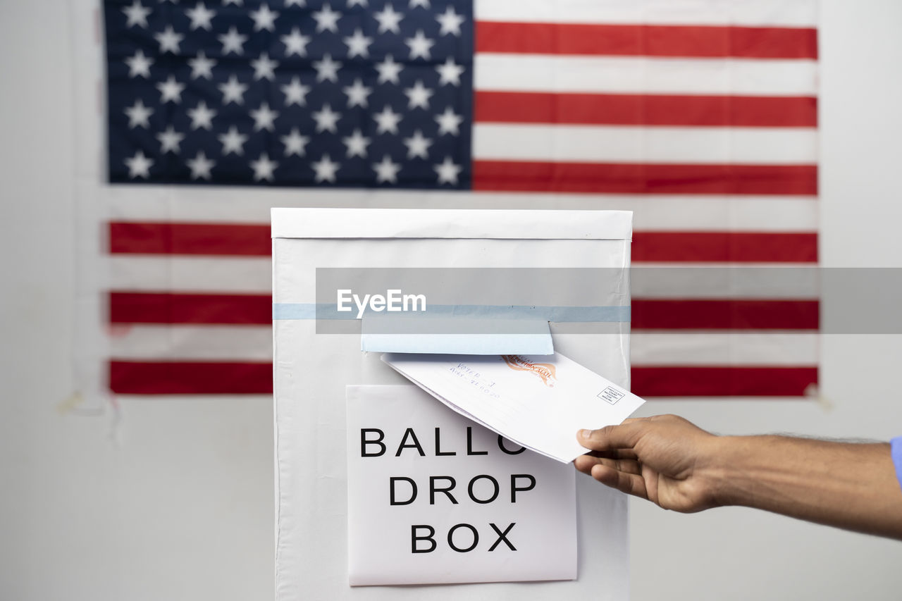 CLOSE-UP OF HAND HOLDING FLAG AGAINST WHITE TEXT