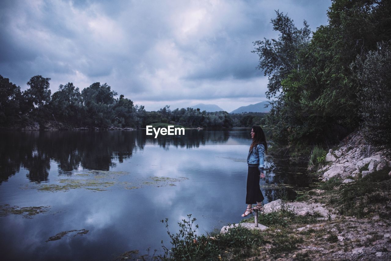 Side view full length of woman standing by lake