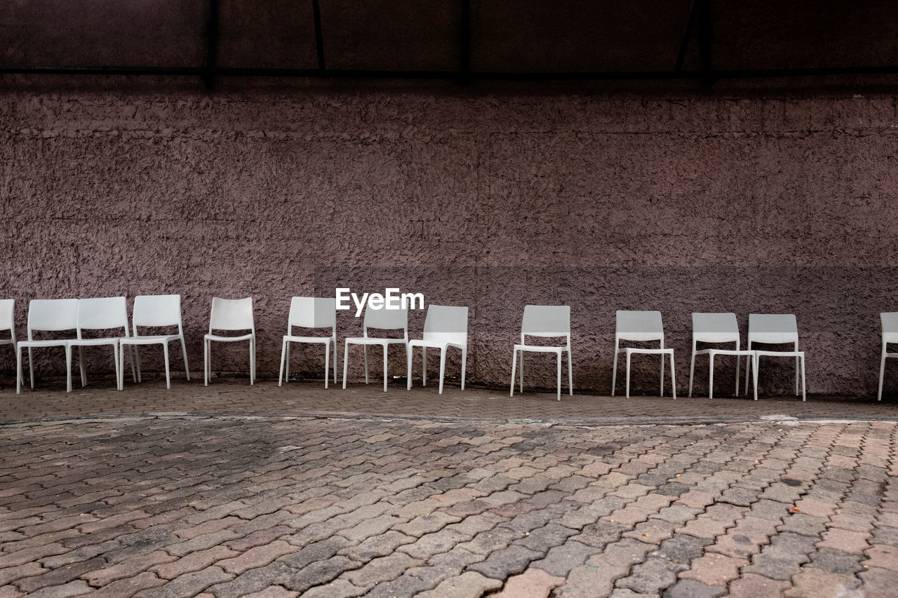Empty chairs against wall in city