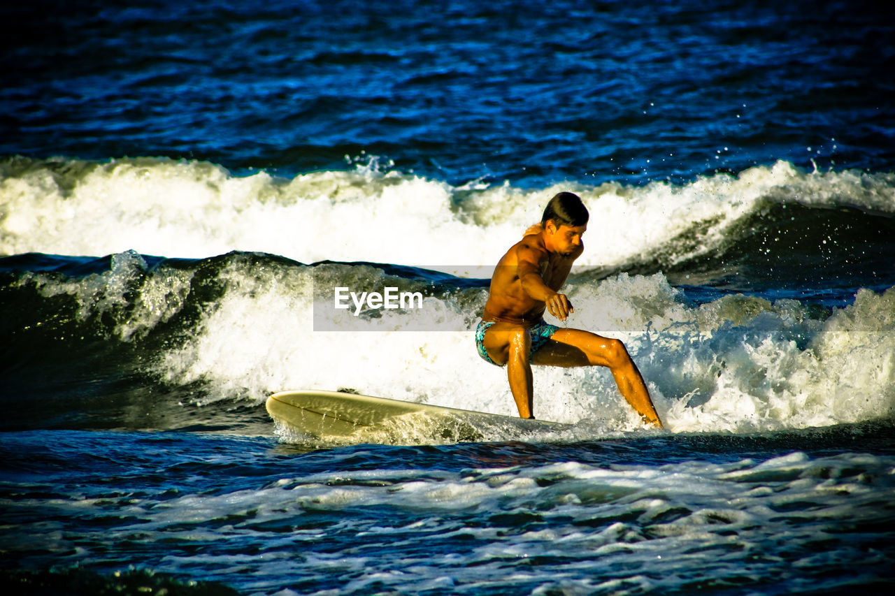 Young man surfboarding on sea